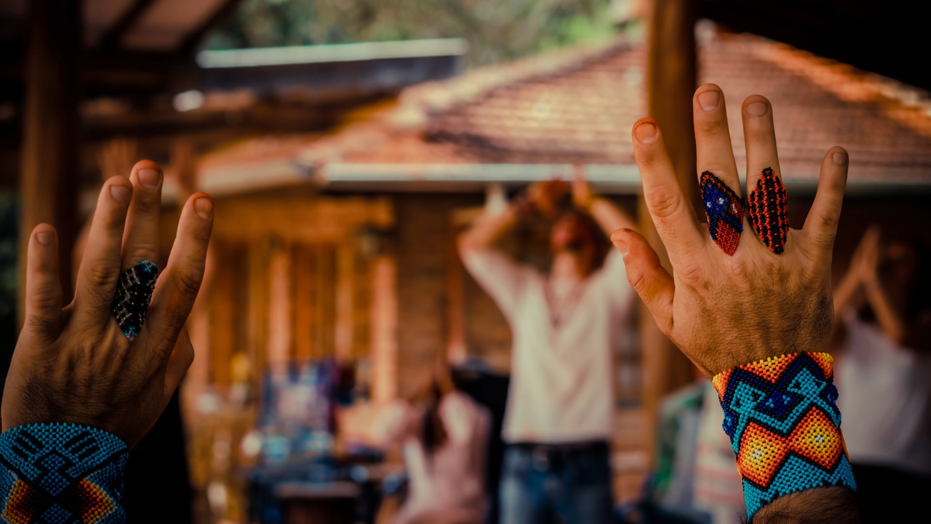 Close-up of hands wearing beaded jewelry, raised in ritual gesture during an ancestral medicine session.