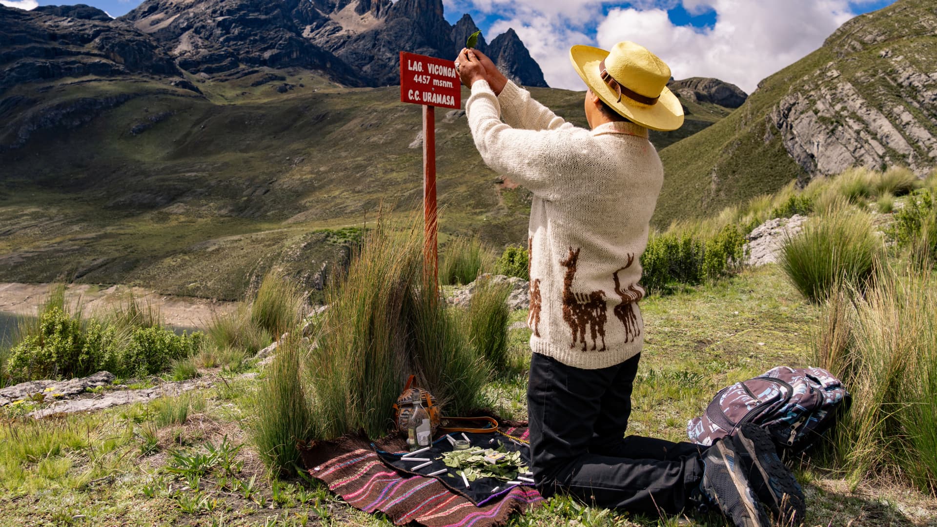 Man in the mountains performing a coca leaf offering ritual, symbolizing respect and spiritual connection with nature.