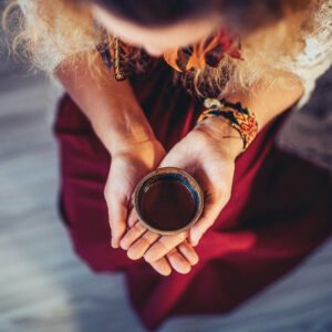 Person holding a ceremonial cup in a traditional healing ritual, focusing on spirituality and inner connection.