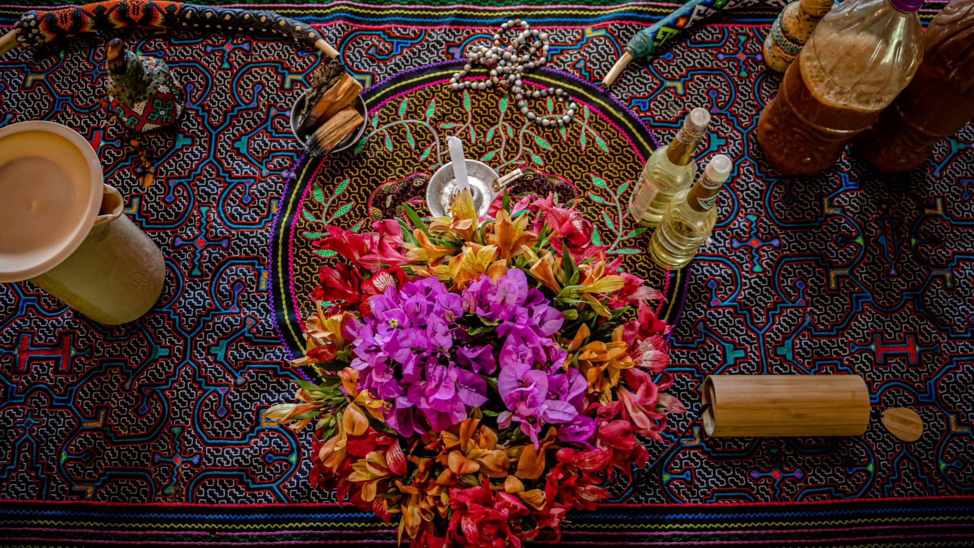 Top view of a traditional Andean altar with colorful flowers, sacred objects, and patterned cloth, symbolizing the richness of Andean spiritual practices.