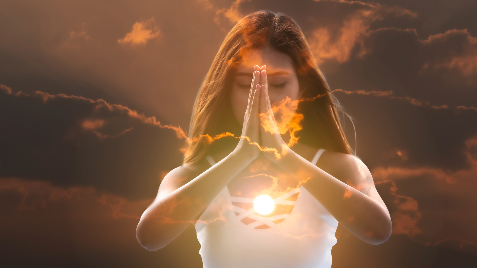 Woman with hands in prayer pose, eyes closed, surrounded by sunlight and clouds, symbolizing spiritual connection and inner peace.