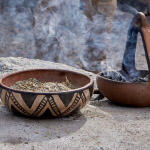 Two clay bowls with incense and herbs releasing smoke during a traditional Andean ceremony, symbolizing spiritual connection and cultural heritage.